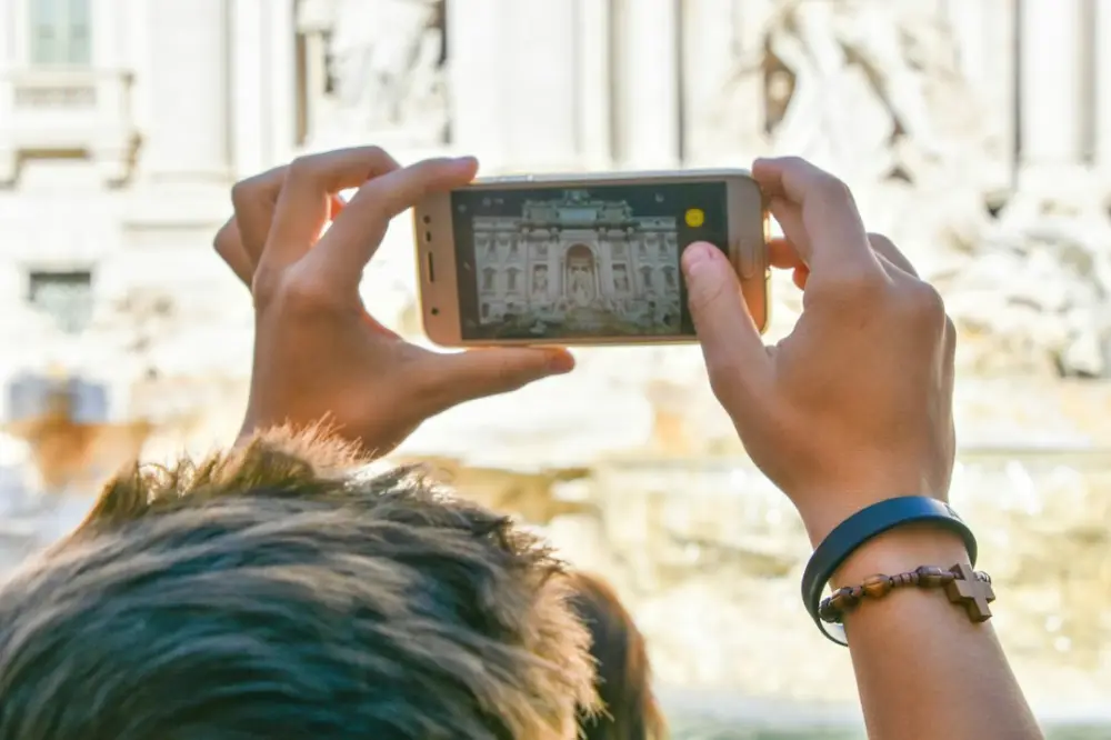 Hands holding a smartphone taking a picture of a building